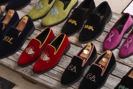 Collection of loafers in various colors with embroidered designs on a wooden surface